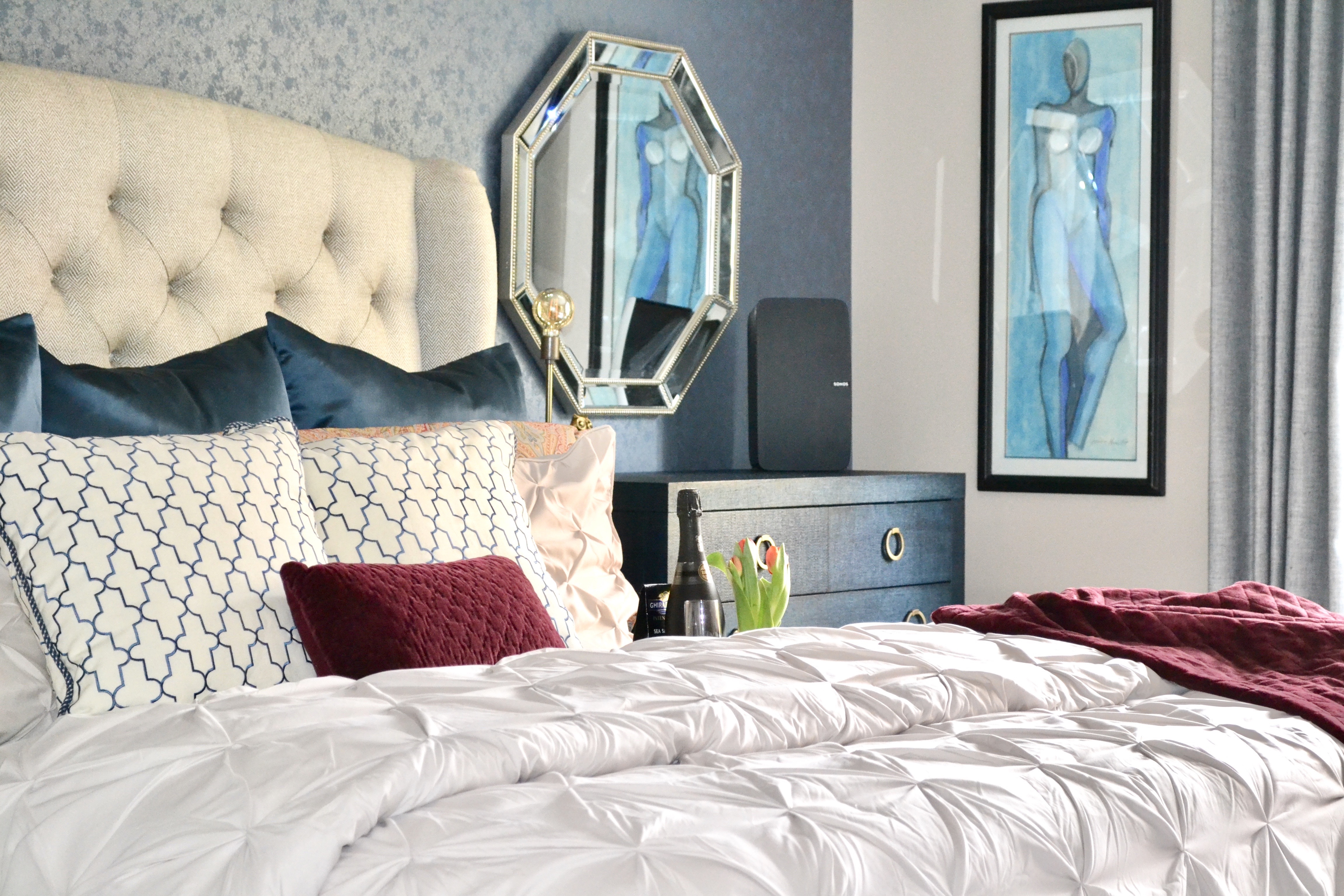 bedroom with blue and red accent colors, and textured floral wallpaper